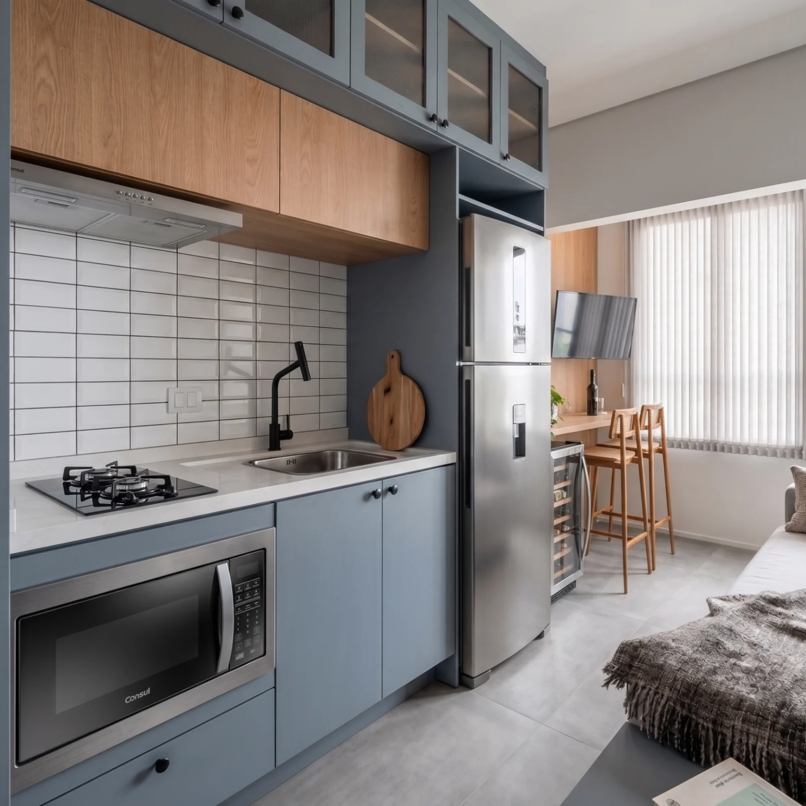 Cozinha de studio com marcenaria cinza, madeira e bancada de refeições
